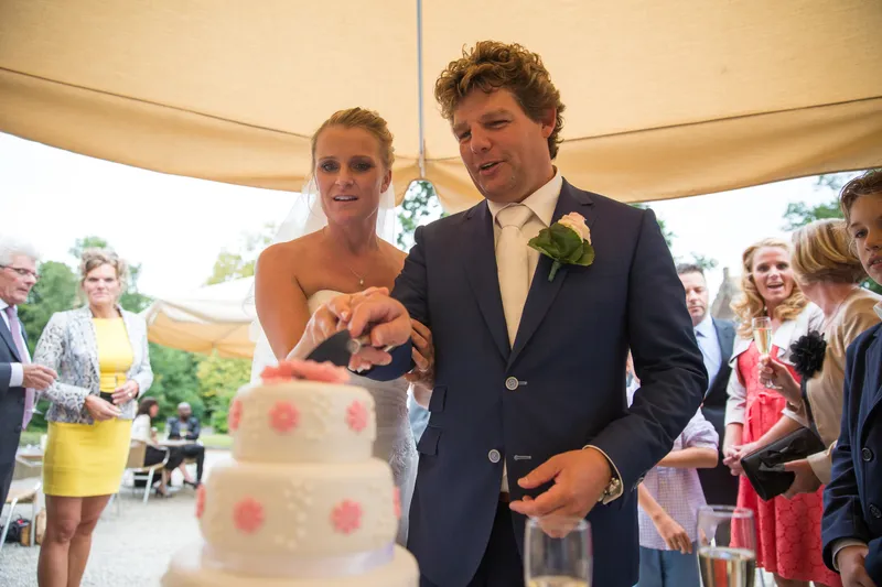 Liselotte en Matthijs snijden de taart aan onder de parasol