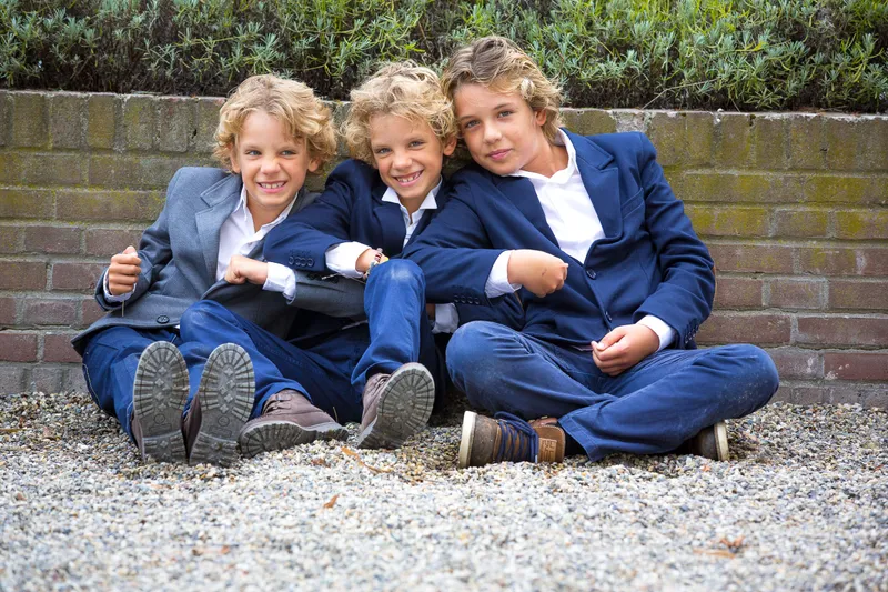 Drie jongens in pak zitten op het grind