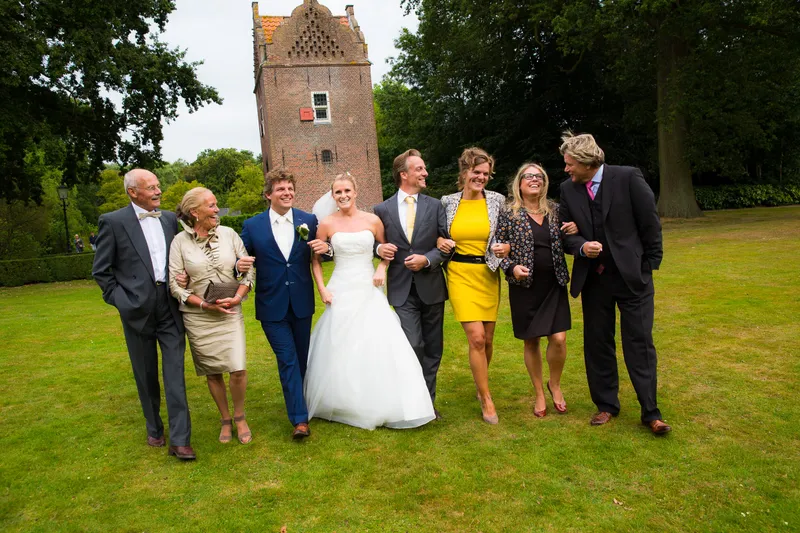 Liselotte en Matthijs lopen met familie over het gazon, met de toren van Te Werve erachter
