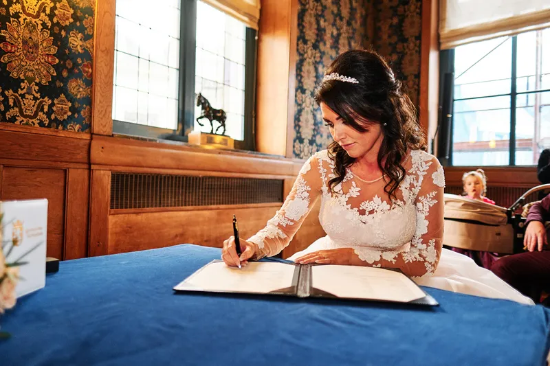 Kimberley zet haar handtekening aan de tafel met het blauwe kleed