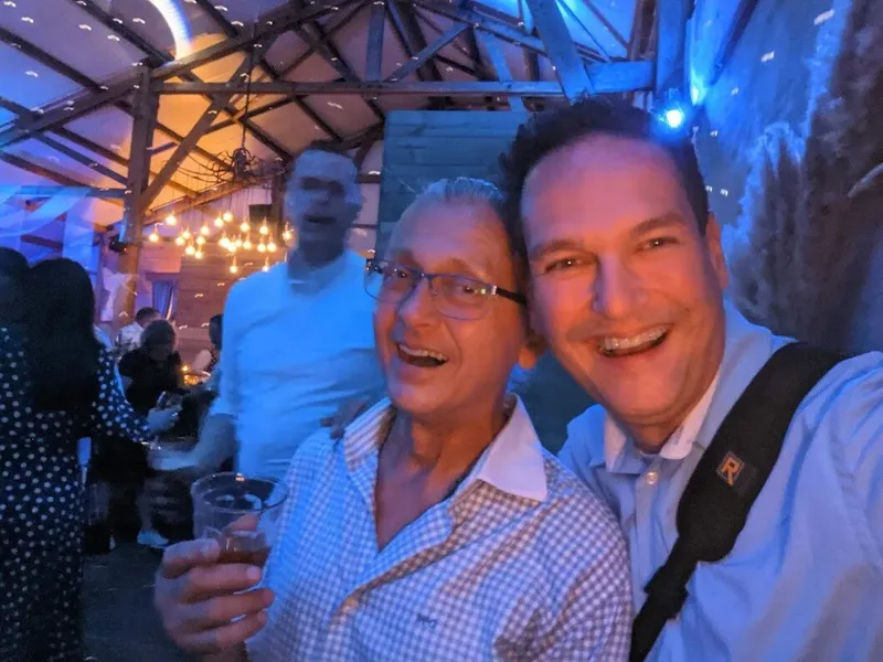 Selfie met een iPhone op een feest: twee lachende mannen, onscherp en met korrel