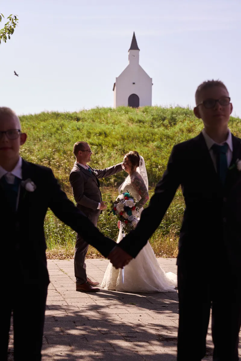 Het gezin hand in hand als silhouet, met het kerkje op de heuvel