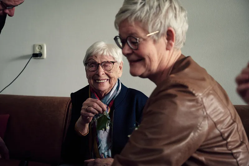 Twee oudere vrouwen lachen samen in de woonkamer