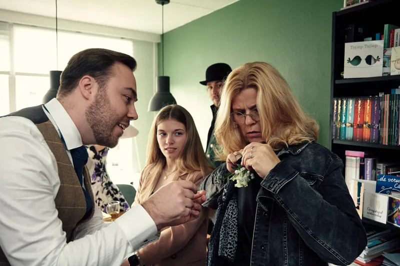 Een corsage wordt opgespeld bij een gast in een spijkerjasje