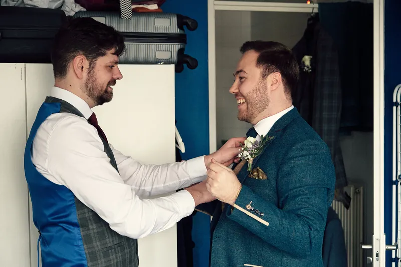 Joey en Twan helpen elkaar met de corsage in de gang