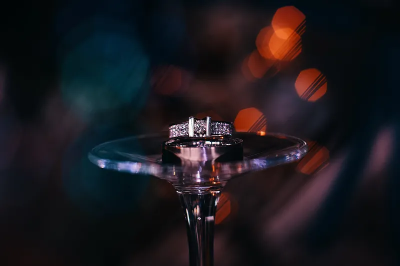 De trouwringen op een glas met lichtjes erachter