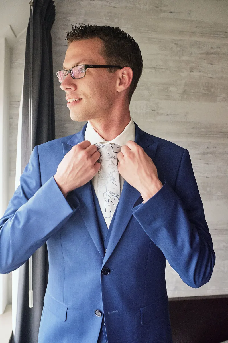 Arjan knoopt zijn blauwe colbert dicht bij het raam