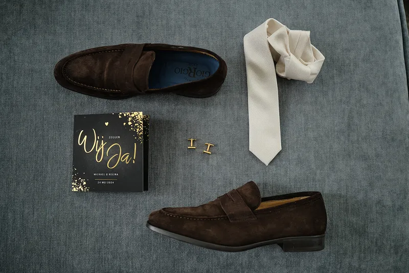 Bruine loafers, een crèmekleurige stropdas, manchetknopen en een kaartje met ‘Wij ja!’