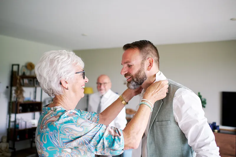 Sander krijgt hulp met zijn corsage van een vrouw met wit haar