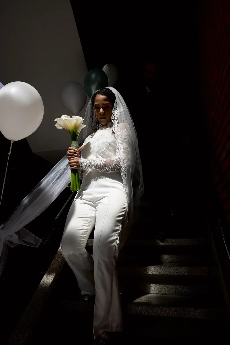 Jennifer komt in haar witte broekpak de trap af, met een ballon