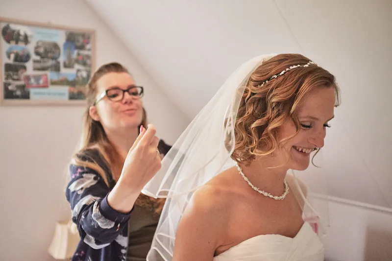 Een vriendin doet lachend de sluier van Femke goed