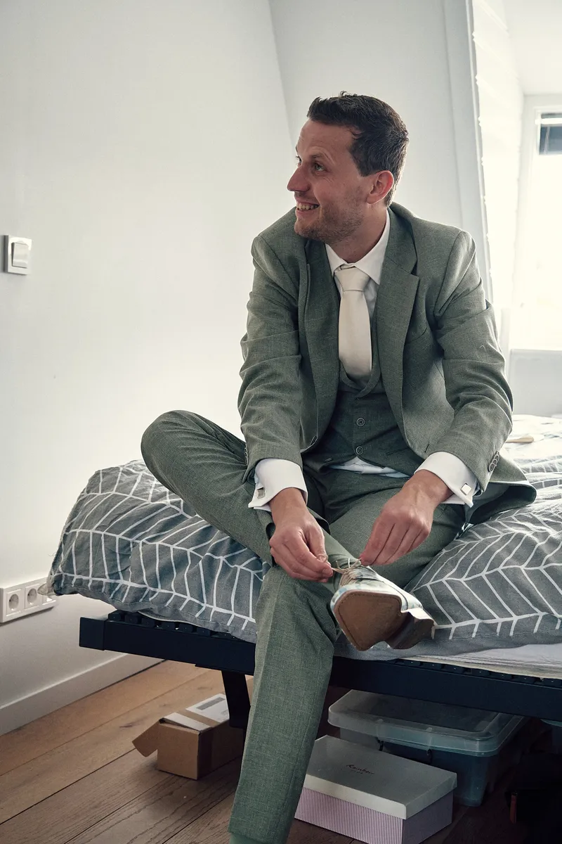 Tijmen strikt zijn veters op de rand van het bed