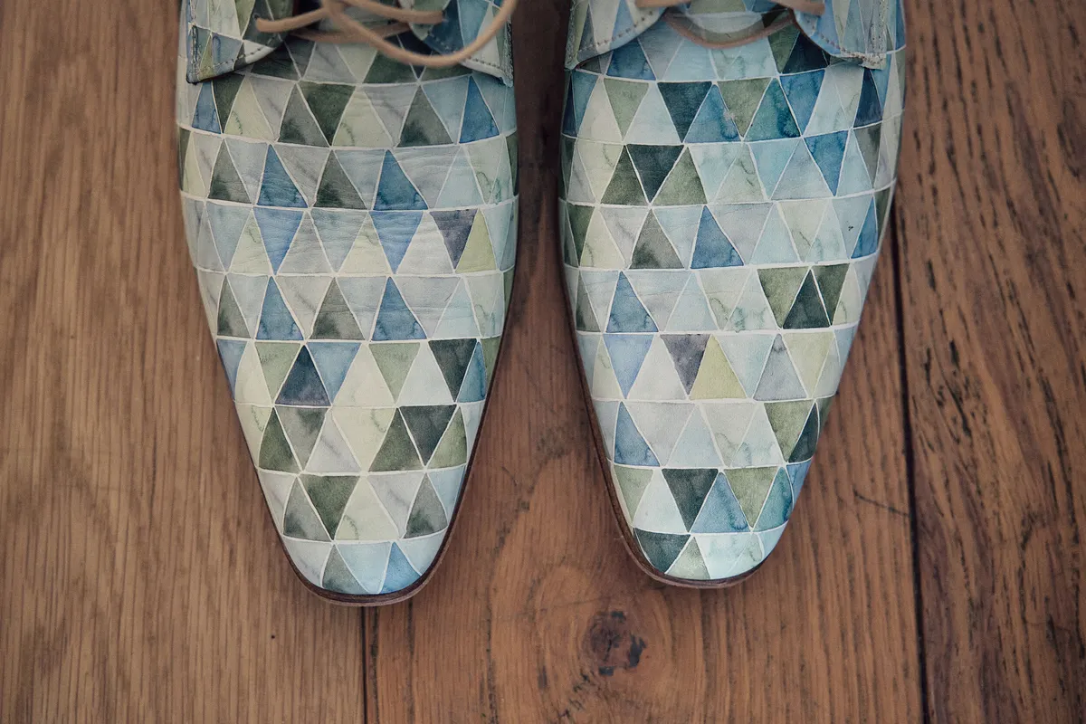 De schoenen van Tijmen met een blauwe driehoekjesprint op de houten vloer