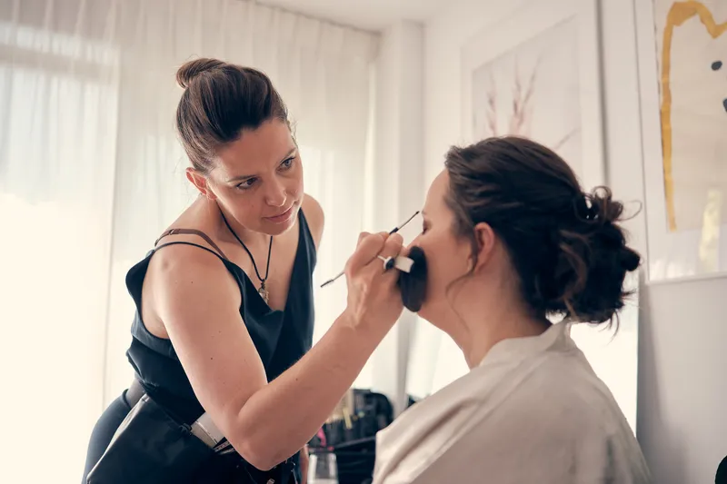 De visagist werkt de make-up van Evelien bij in de woonkamer