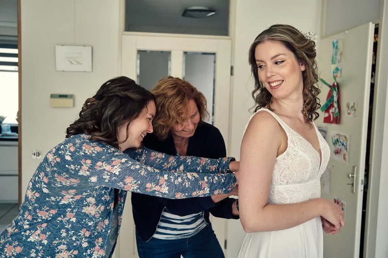 Twee vrouwen maken lachend de jurk van Renske dicht