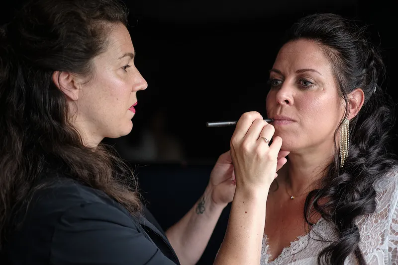 De visagiste werkt de lippenstift van Regina bij, in haar jurk