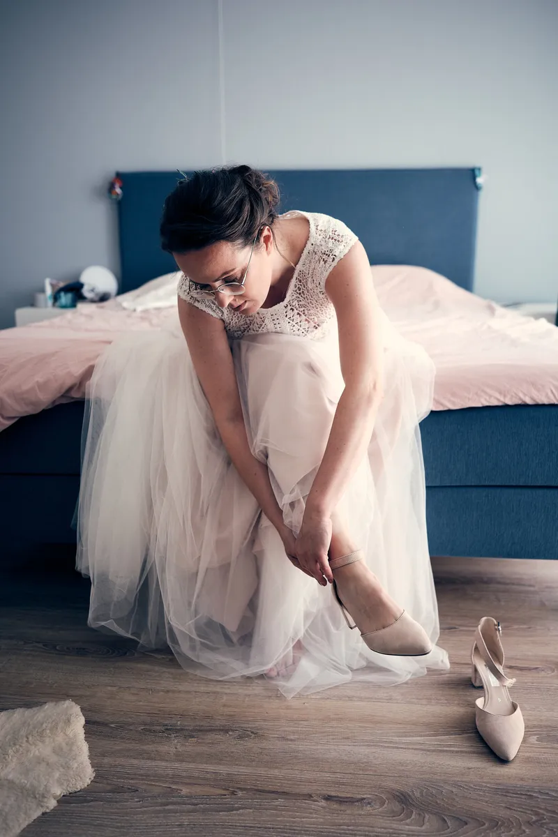 Evelien trekt op de rand van het bed haar schoenen aan