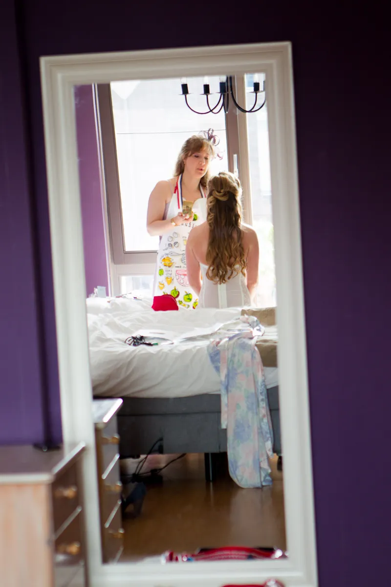 Anouk in de spiegel van de slaapkamer, terwijl haar haar wordt gedaan