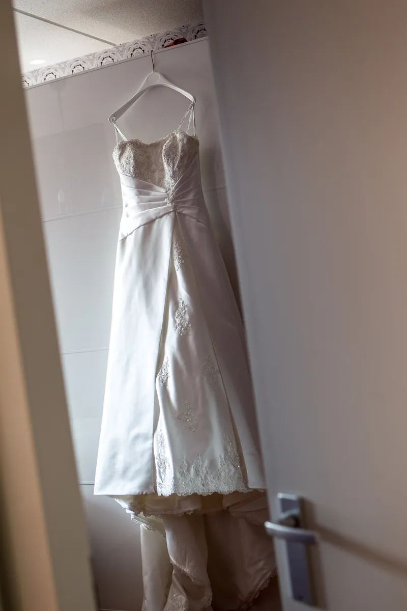 De trouwjurk hangt aan de deur