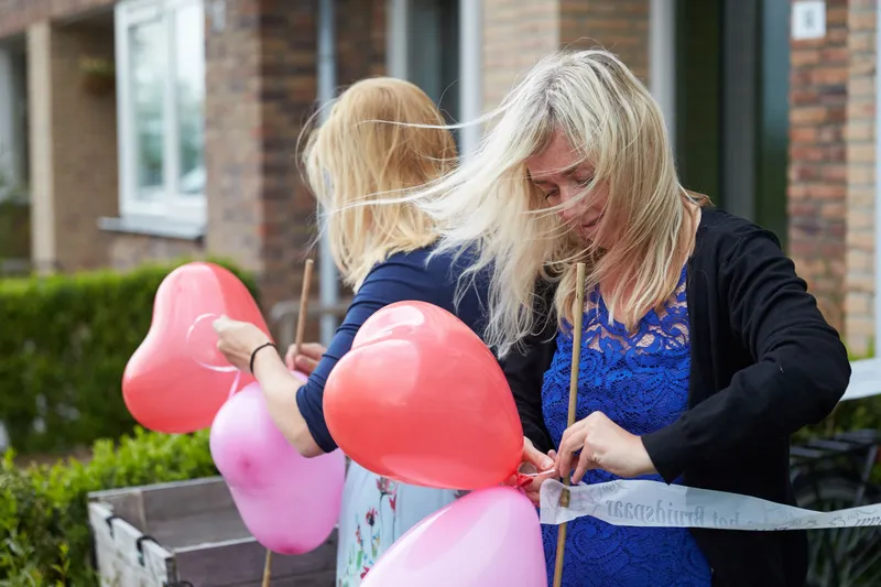 Marina’s zussen binden roze en rode hartjesballonnen aan een lint