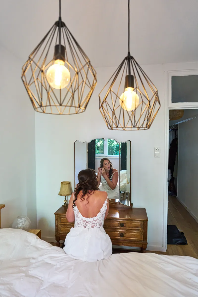 Michelle zit in haar jurk op het bed, met haar rug naar de camera