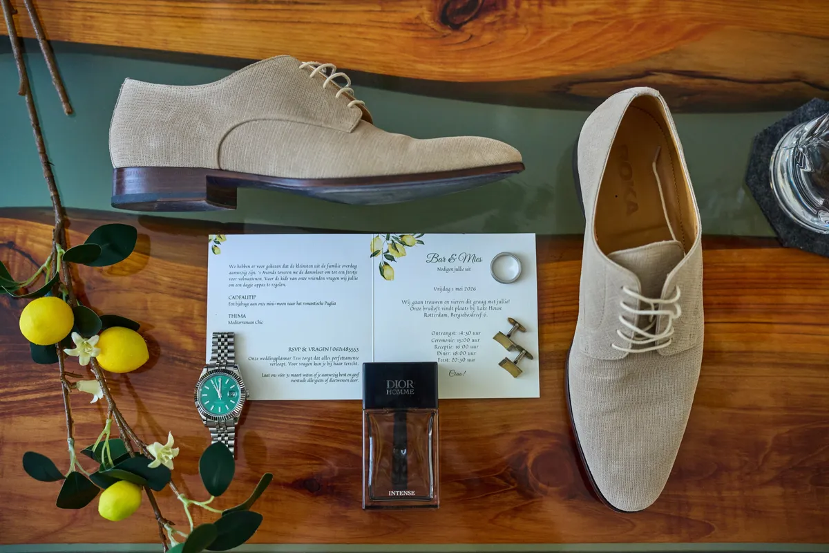 Schoenen, horloge, parfum en de uitnodiging op een houten tafel met citroenen