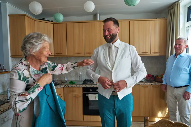 Barrie in zijn witte colbert in de keuken, zijn ouders kijken toe