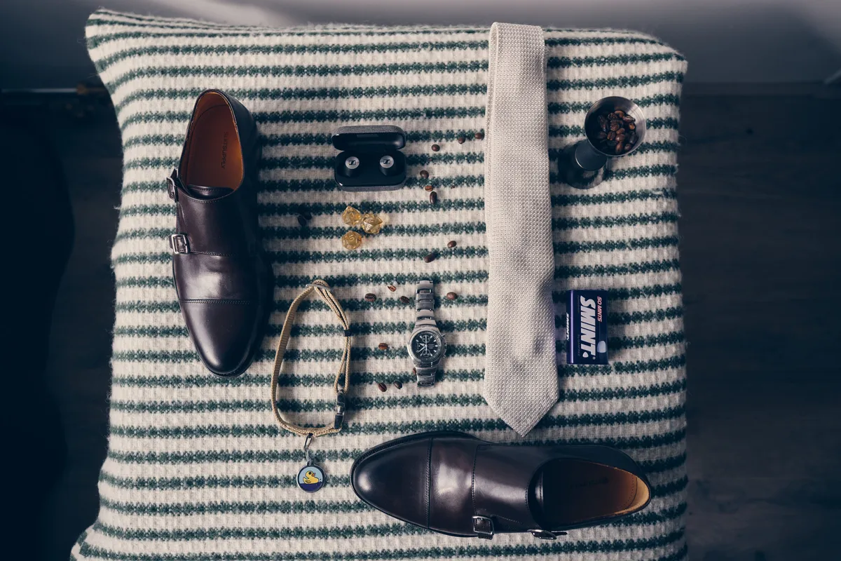 Schoenen, horloge, manchetknopen en een das op een gestreepte deken