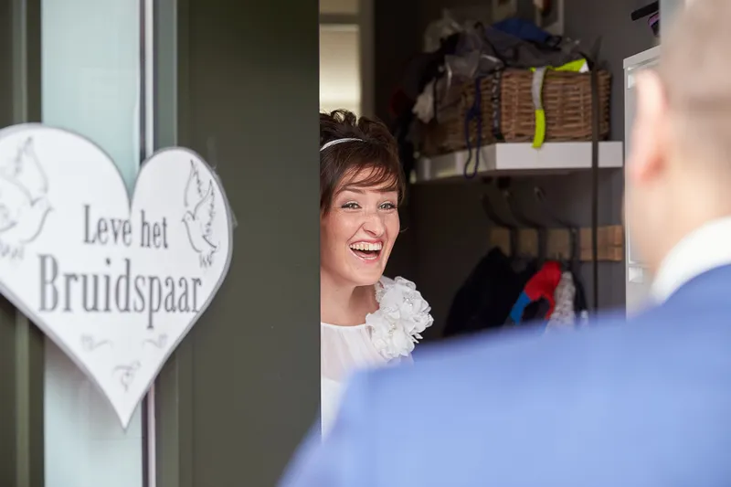 Marina lacht in de deuropening, Erik staat met zijn rug naar de camera