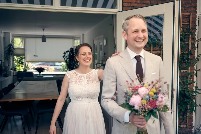 Evelien en Krijn stralend in de tuindeuren, Krijn met het boeket