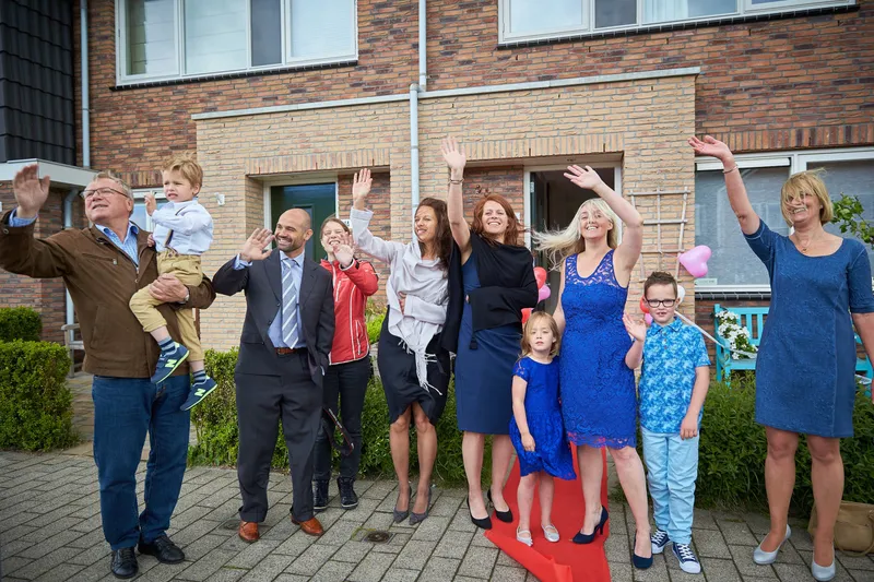 De familie zwaait vanaf de stoep