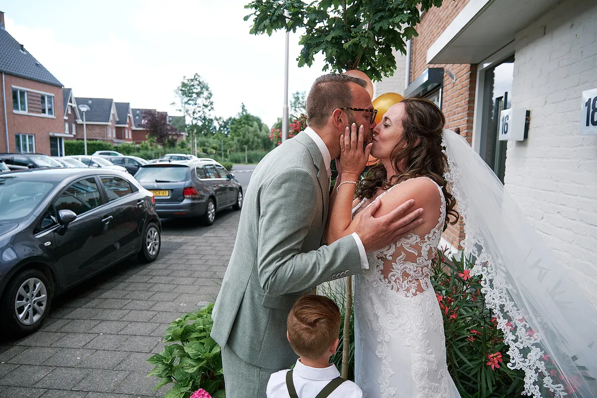 Sander en Romana kussen op de stoep, met hun zoon tussen hen in