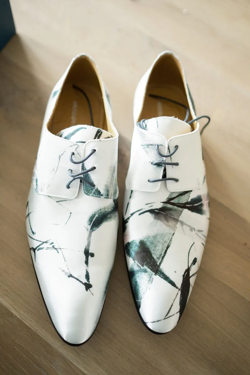 De beschilderde witte schoenen van Jasper op de houten vloer