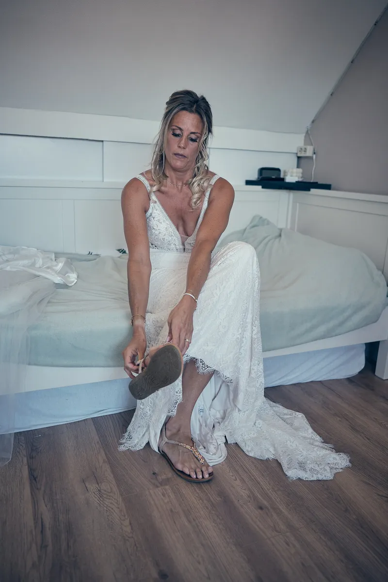 Jolanda doet haar sandalen aan op de rand van het bed
