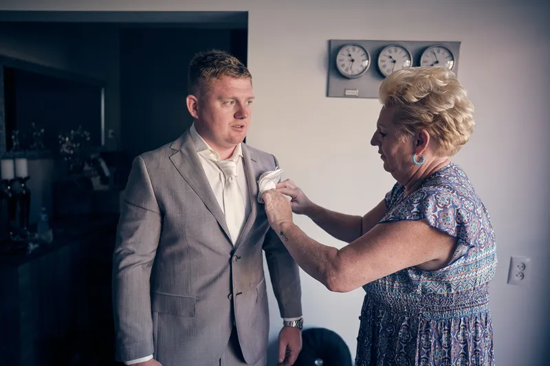 De moeder van Jordy speldt zijn corsage op