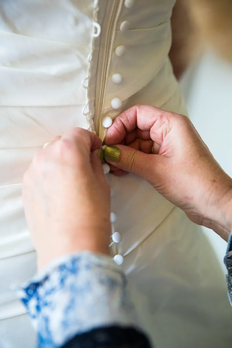 De knoopjes op de rug van de jurk worden dichtgemaakt