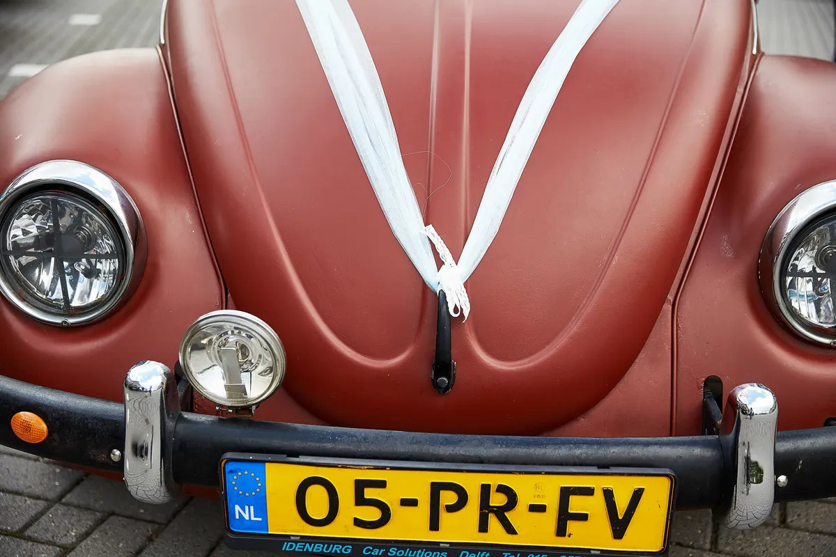 De rode Kever met een wit lint op de motorkap