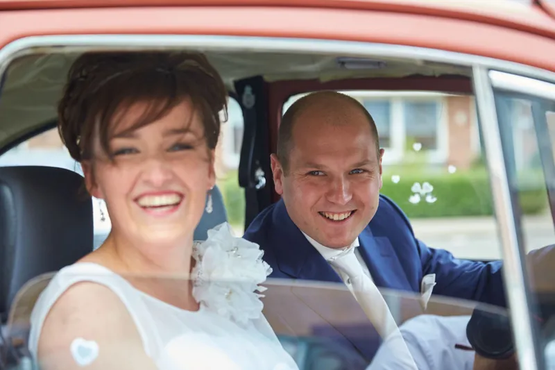 Marina en Erik lachen in de rode Kever