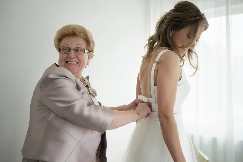 Een familielid maakt de jurk van Mary dicht