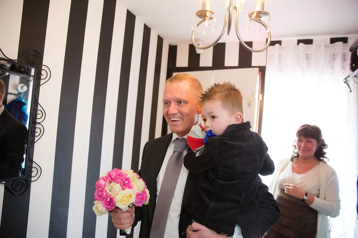 Sven met hun zoontje en het boeket in de woonkamer