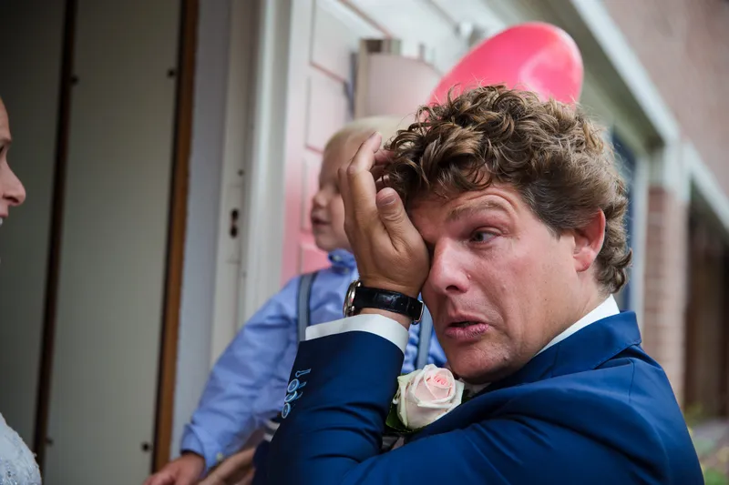 Matthijs veegt een traan weg, hun zoontje staat naast hem