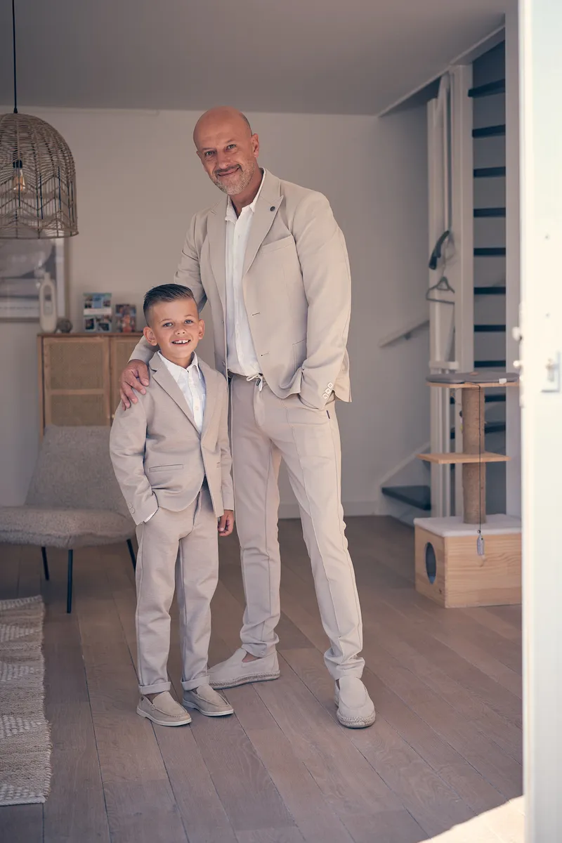 Pascal en zijn zoon in bijpassende pakken in de woonkamer