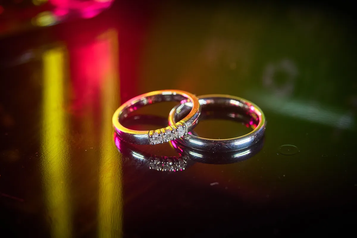 De trouwringen op een donker oppervlak met rood en geel licht