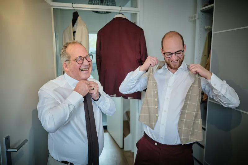 Tim en zijn vader lachen terwijl ze hun gilet aantrekken