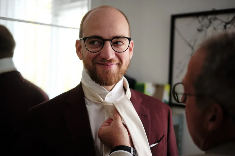 Tim glimlacht terwijl zijn vader zijn das strikt