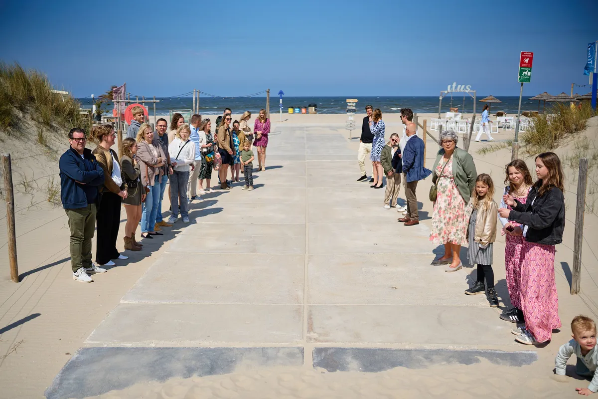 De gasten wachten op het vlonderpad naar het strand
