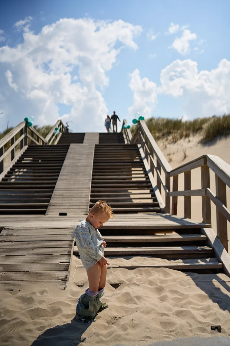 Hun zoontje op de trap naar het strand