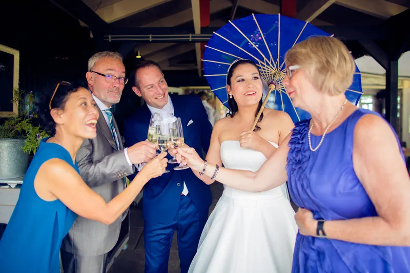 Anne-Floor en Hans proosten met familie, met een blauwe parasol