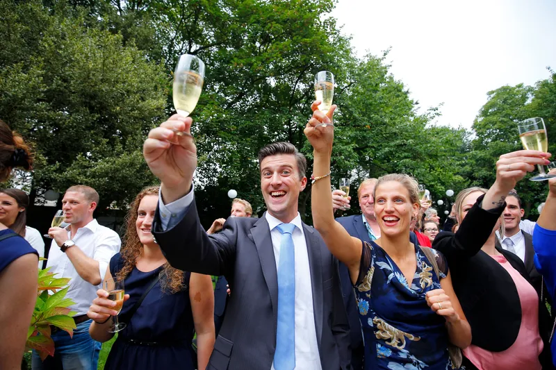 De gasten heffen het glas in de tuin