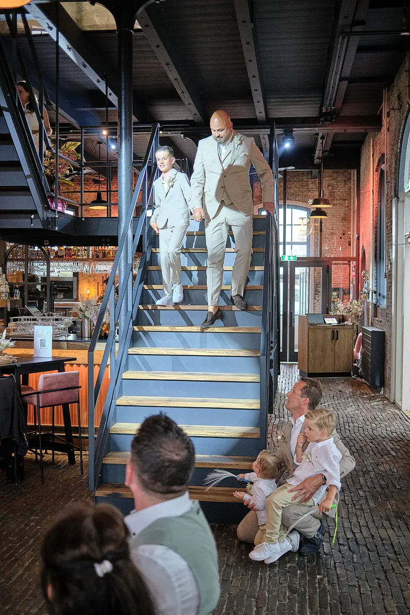 Het bruidspaar komt met hun kinderen de stalen trap af, de zaal in